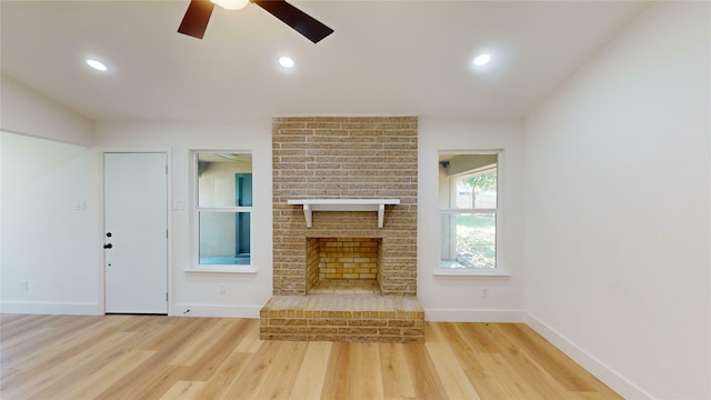 unfurnished living room with ceiling fan, light hardwood / wood-style flooring, and a brick fireplace