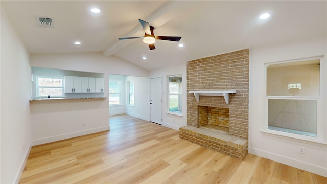 unfurnished living room with a brick fireplace, light wood-type flooring, vaulted ceiling with beams, and plenty of natural light