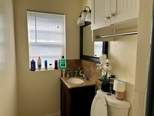 bathroom featuring vanity, plenty of natural light, toilet, and decorative backsplash