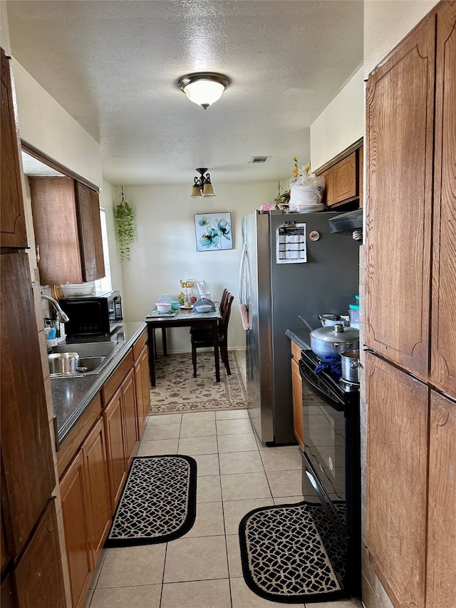 kitchen featuring a textured ceiling, sink, black appliances, exhaust hood, and light tile patterned floors