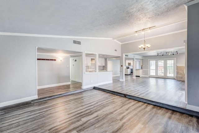 unfurnished living room with french doors, a textured ceiling, an inviting chandelier, hardwood / wood-style floors, and lofted ceiling