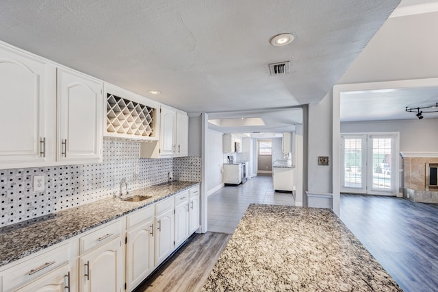 kitchen featuring white cabinets, wood-type flooring, dark stone counters, and sink