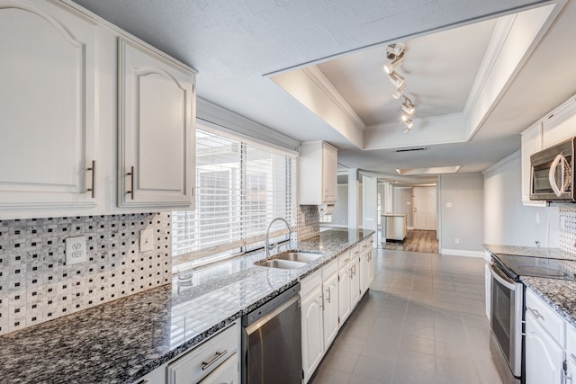 kitchen featuring appliances with stainless steel finishes, tasteful backsplash, a raised ceiling, sink, and white cabinetry