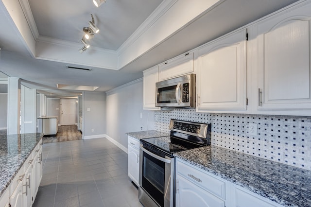 kitchen featuring dark stone counters, white cabinetry, ornamental molding, and appliances with stainless steel finishes