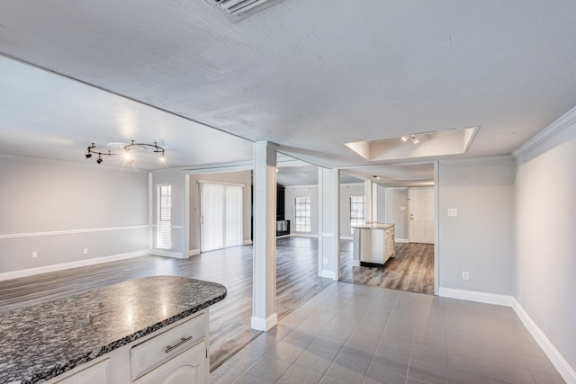 kitchen with a raised ceiling, white cabinetry, light hardwood / wood-style flooring, and crown molding