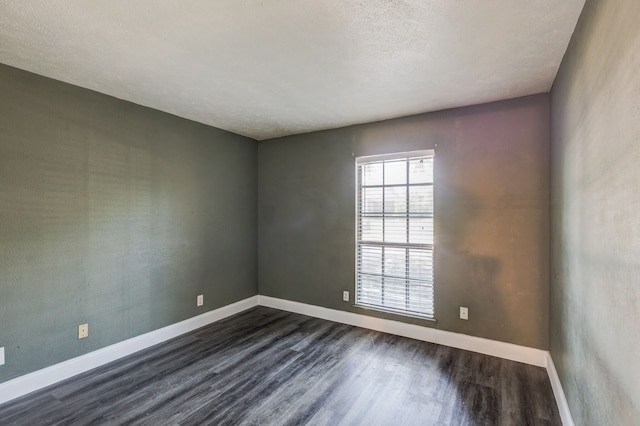 spare room with a textured ceiling and dark hardwood / wood-style flooring