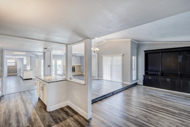 kitchen with white cabinetry, an inviting chandelier, dark hardwood / wood-style floors, vaulted ceiling, and ornamental molding