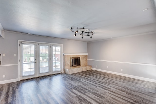 unfurnished living room featuring a fireplace, dark hardwood / wood-style flooring, crown molding, and french doors