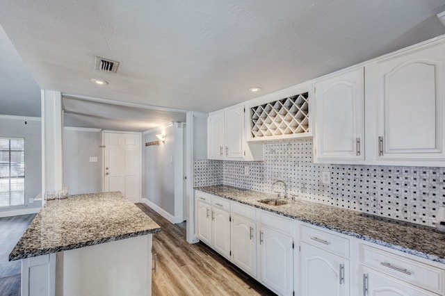 kitchen featuring white cabinetry, light hardwood / wood-style flooring, ornamental molding, and sink