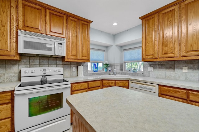 kitchen featuring backsplash, sink, and white appliances