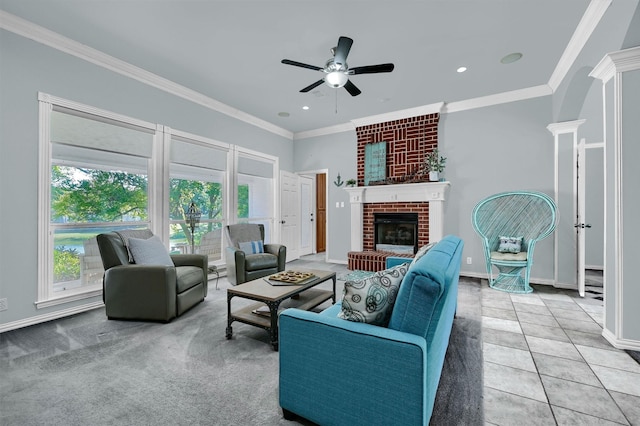 carpeted living room with ceiling fan, a brick fireplace, a wealth of natural light, and ornate columns