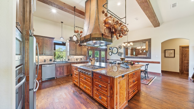 kitchen with light stone countertops, stainless steel appliances, dark wood-type flooring, beam ceiling, and a center island