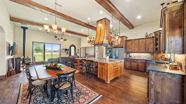 dining space featuring dark hardwood / wood-style flooring, sink, a notable chandelier, beamed ceiling, and a wood stove