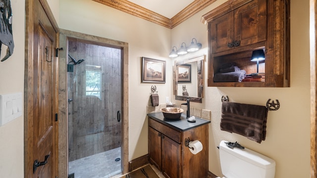 bathroom with crown molding, vanity, a shower with shower door, and toilet