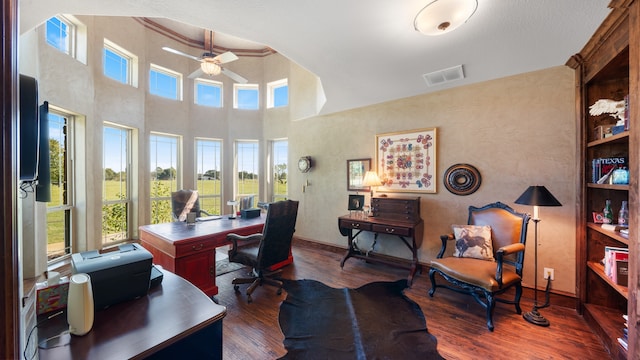 home office with a high ceiling, dark hardwood / wood-style floors, ceiling fan, and built in shelves