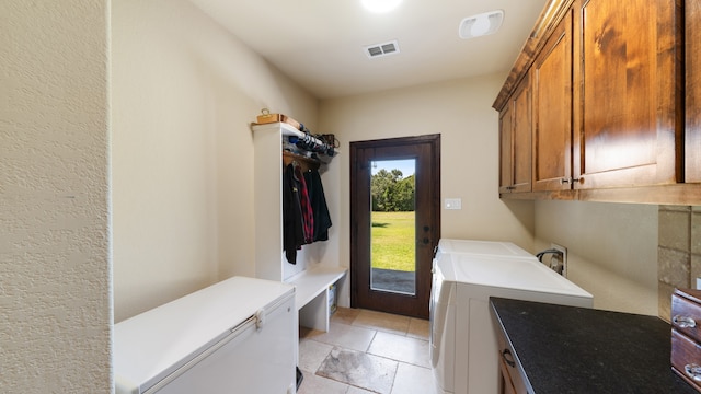 clothes washing area with washer and dryer and cabinets