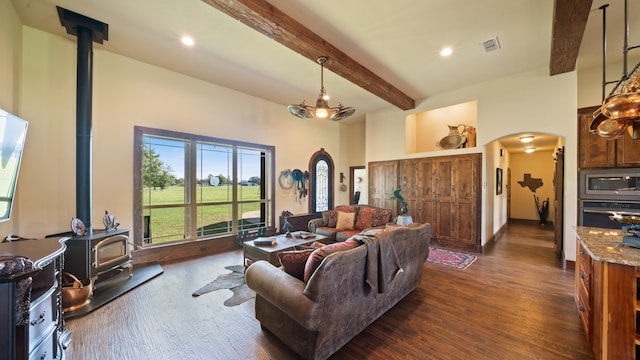 living room featuring a wood stove, beamed ceiling, and dark wood-type flooring