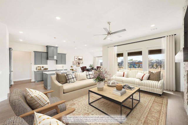 living room with ceiling fan, sink, and light wood-type flooring