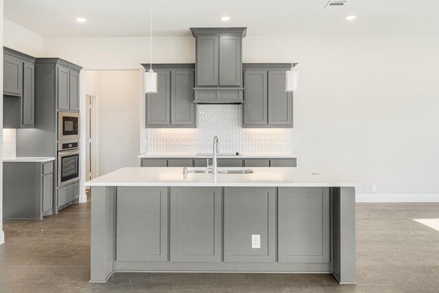 kitchen with sink, gray cabinetry, tasteful backsplash, hanging light fixtures, and oven