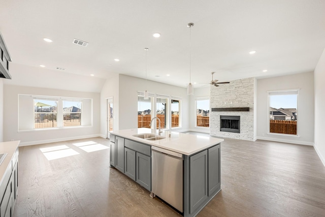 kitchen featuring sink, gray cabinetry, decorative light fixtures, a center island with sink, and dishwasher