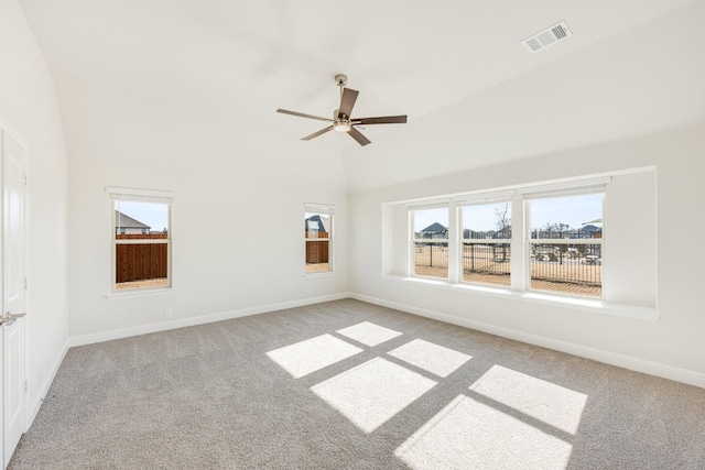 empty room with ceiling fan, vaulted ceiling, and light carpet