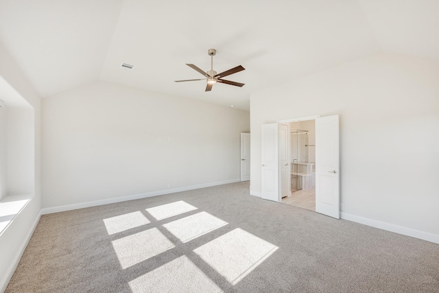 unfurnished bedroom with lofted ceiling, light colored carpet, ceiling fan, and ensuite bath