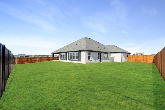 rear view of house featuring cooling unit and a lawn