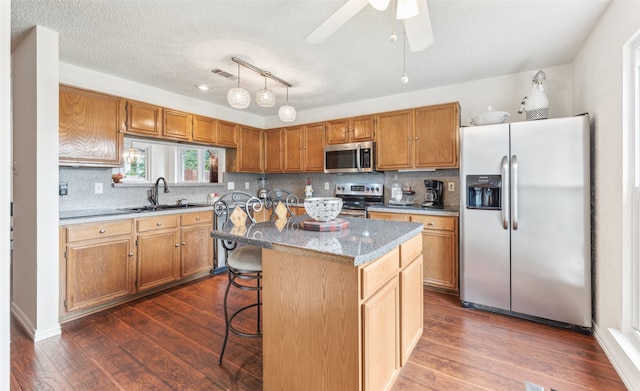 kitchen featuring a breakfast bar, sink, a kitchen island, appliances with stainless steel finishes, and dark hardwood / wood-style flooring