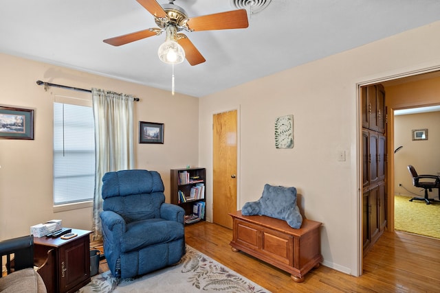 living area with ceiling fan and light hardwood / wood-style flooring