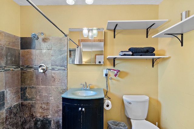 bathroom featuring a tile shower, vanity, and toilet