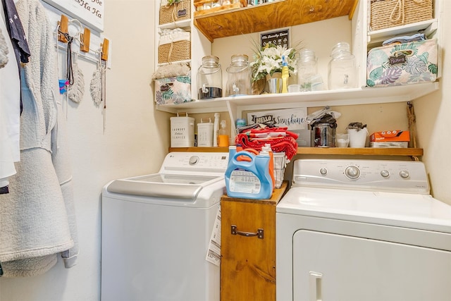 clothes washing area with separate washer and dryer and cabinets