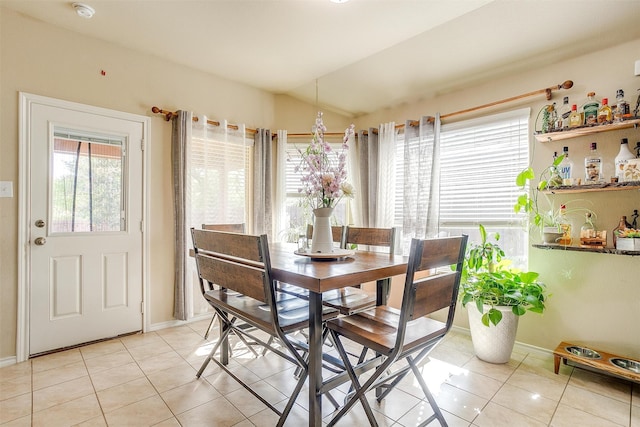 dining space with light tile patterned flooring and lofted ceiling