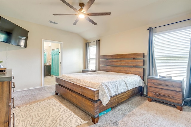 bedroom featuring light carpet, vaulted ceiling, connected bathroom, and ceiling fan