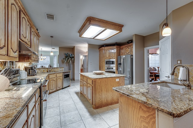 kitchen featuring light stone counters, hanging light fixtures, sink, a kitchen island, and stainless steel appliances