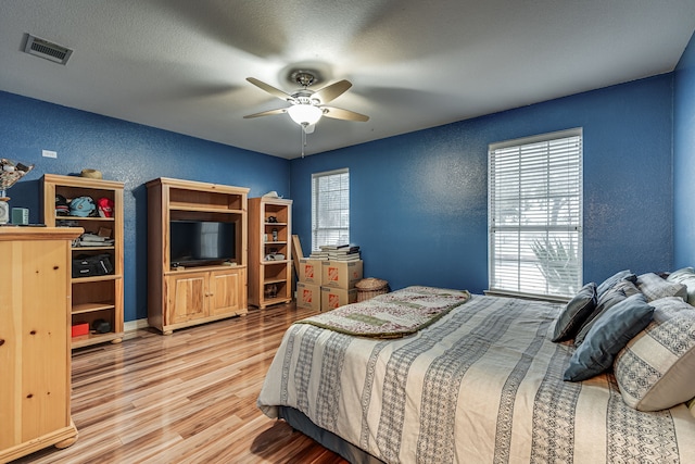 bedroom featuring light wood-type flooring, a textured ceiling, and ceiling fan