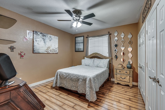 bedroom featuring light wood-type flooring, a textured ceiling, and ceiling fan