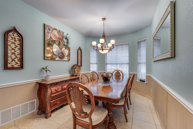 tiled dining space featuring wood walls and an inviting chandelier