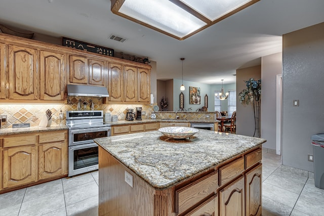 kitchen with appliances with stainless steel finishes, light tile patterned flooring, a center island, and decorative light fixtures