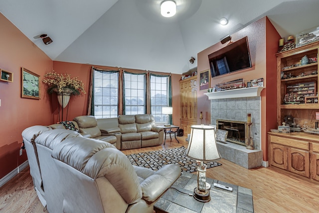 living room with light wood-type flooring, lofted ceiling, and a tile fireplace