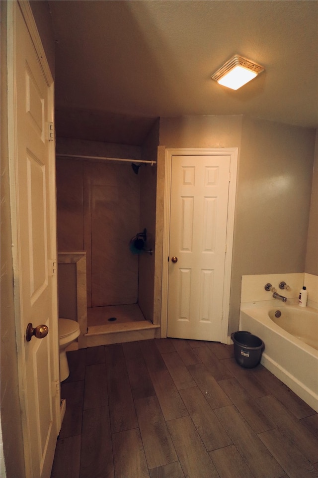 bathroom featuring wood-type flooring, shower with separate bathtub, and toilet