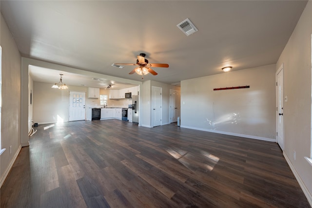 unfurnished living room with ceiling fan with notable chandelier and dark hardwood / wood-style floors