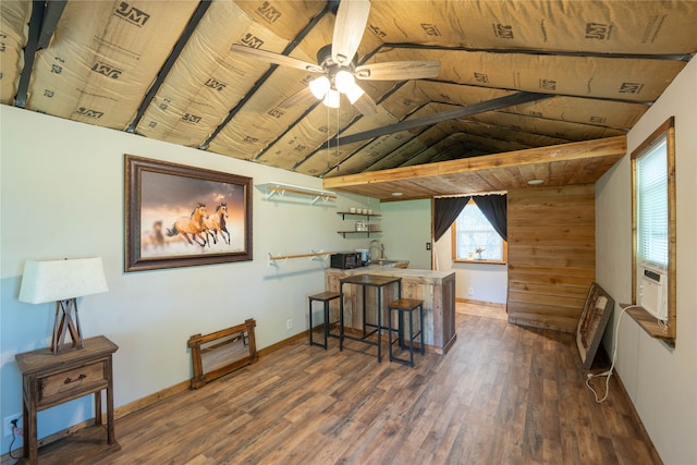 interior space with wood ceiling, dark hardwood / wood-style floors, vaulted ceiling, kitchen peninsula, and a kitchen breakfast bar