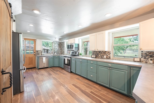 kitchen featuring light hardwood / wood-style flooring, stainless steel appliances, white cabinets, and tasteful backsplash