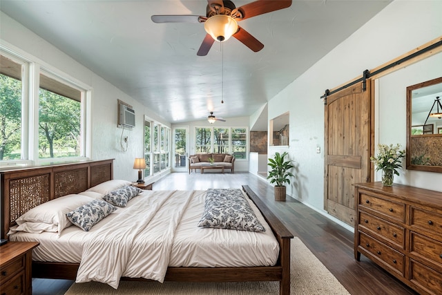 bedroom with a barn door, lofted ceiling, dark hardwood / wood-style flooring, and multiple windows