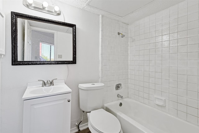 full bathroom featuring tiled shower / bath, vanity, and toilet