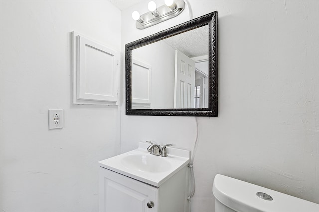 bathroom with vanity, toilet, and a textured ceiling