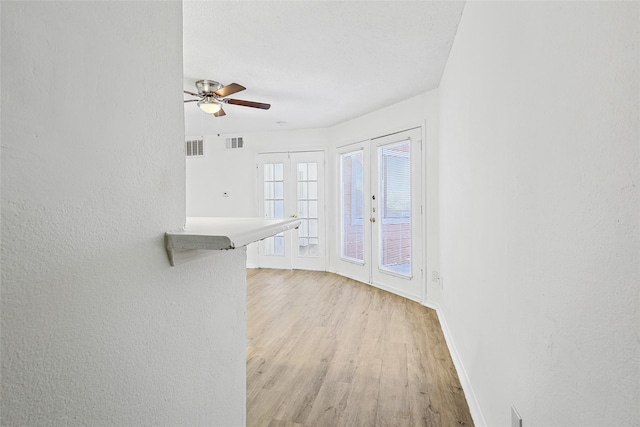 unfurnished living room featuring french doors, a textured ceiling, light hardwood / wood-style flooring, and ceiling fan