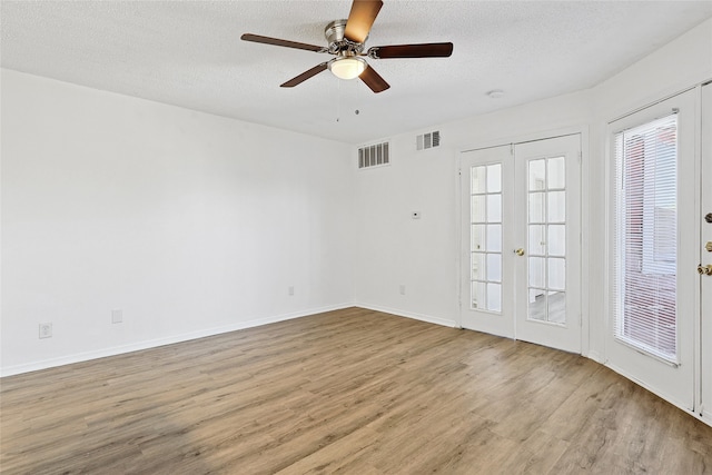 spare room featuring light wood-type flooring, a textured ceiling, ceiling fan, and french doors