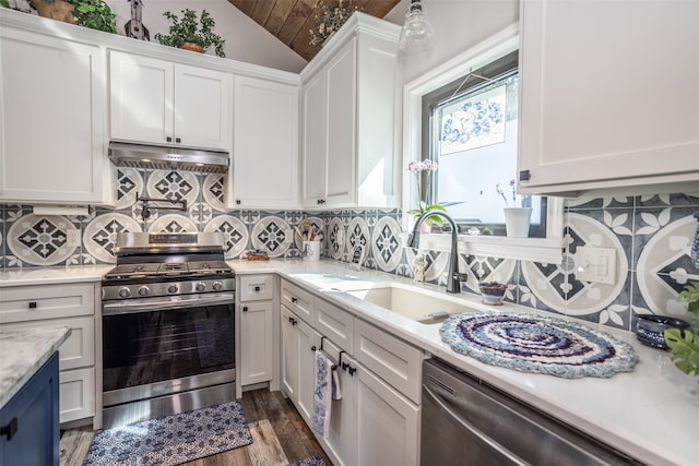 kitchen with vaulted ceiling, white cabinets, backsplash, stainless steel appliances, and sink