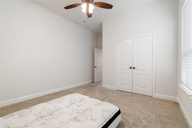 unfurnished bedroom featuring a closet, light colored carpet, and ceiling fan